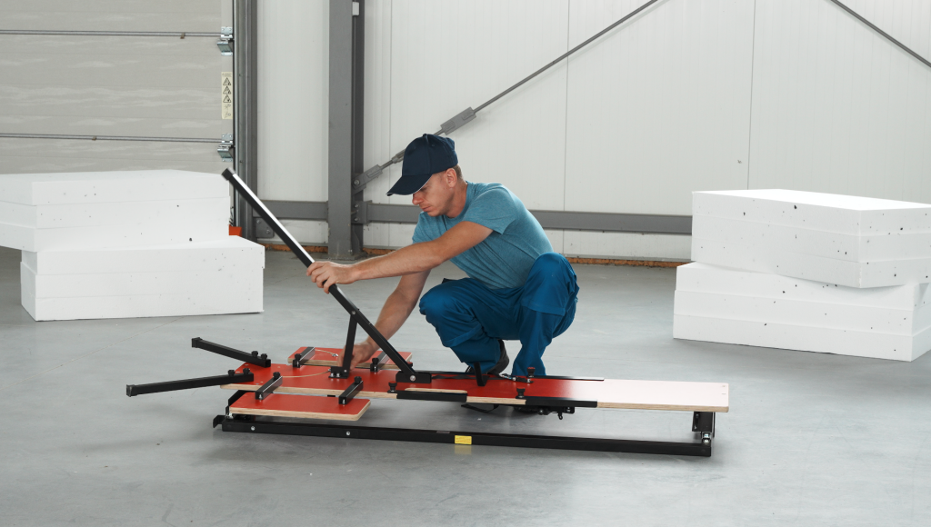 Człowiek używający maszyny do wycinania w styropianach do cięcia bloków piankowych.