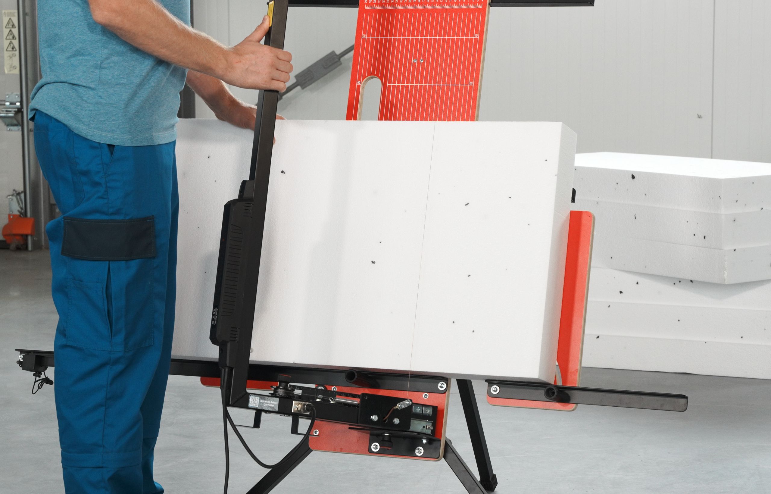 Osoba řezající pěnovou desku pomocí vertikálního řezacího stroje