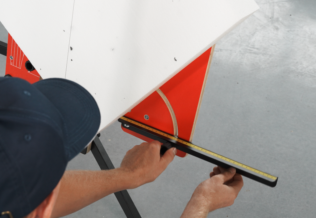 Człowiek odmierzający styropian linijką na maszynie do wycinania w styropianach.